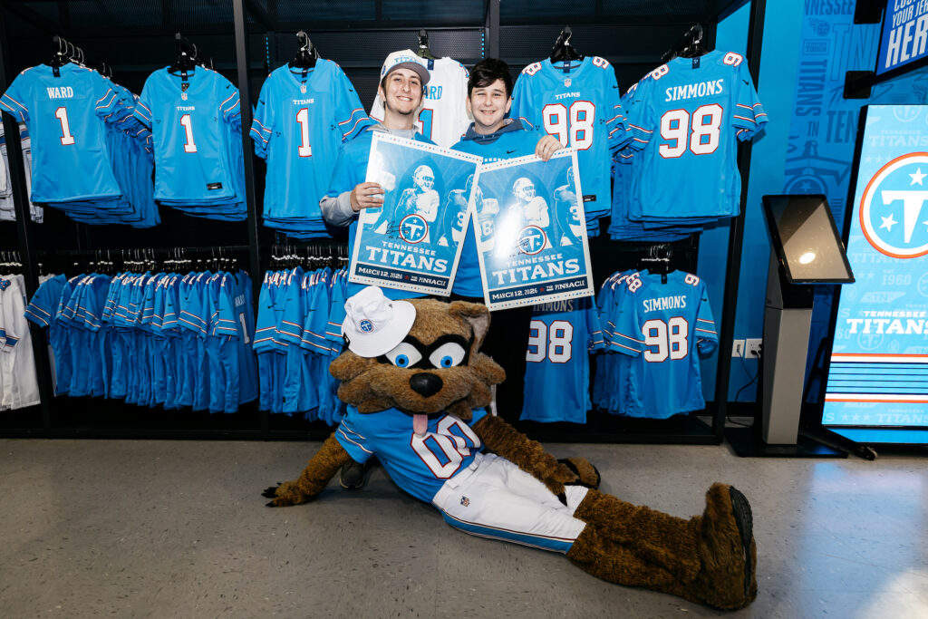 Mascot T-Rac posing with two fans in the Titans Team Store